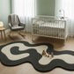 Nursery room with a crib, rocking chair, and abstract rug.
