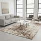 Modern living room with a gray sofa, coffee table, and chairs on a patterned rug.