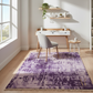 Home office with a purple patterned rug, desk, and chair.
