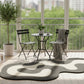 Outdoor seating area with a table and chairs on a balcony with a cityscape view.