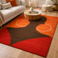 Living room with a red and brown abstract rug, beige sofa, and wooden coffee table.