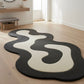 Modern black and white abstract rug on a wooden floor with a minimalistic room setting.