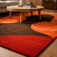 Round wooden coffee table on a multicolored rug in a living room setting.