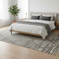 Bedroom with a bed, nightstands, and a rug on a wooden floor.