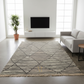 Modern living room with a geometric patterned rug, gray sofa, and white entertainment unit.