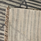 Close-up of a textured rug with striped pattern and frayed edge.