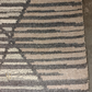 Close-up of a textured rug with geometric pattern on a concrete floor.