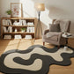 Modern living room with a cloud-shaped rug, bookshelf, and armchair.