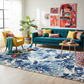 Modern living room with a blue sofa, yellow armchair, and colorful rug.