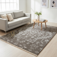 Living room with a gray sofa, round wooden coffee table, and patterned rug.