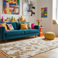 Living room with a blue sofa, colorful cushions, and a patterned rug.