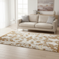 Beige sofa in a living room with a patterned rug on a wooden floor.