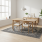 Dining area with wooden table and chairs in a bright room.