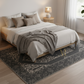 Neatly made bed with white bedding and gray throw blanket on a patterned rug in a bedroom.