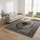 Living room with a gray sofa, coffee table, and chairs on a patterned rug.