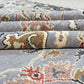 Stack of patterned rugs with intricate designs on a neutral background