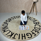 Beige patterned Alphabetical rug on a floor with a kid reading a book