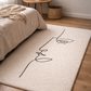 Beige rug with a black line art design of a face in a bedroom setting.