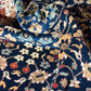 Close-up of a patterned fabric with intricate designs on a dark blue background.