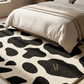 Black and white patterned rug with a gold logo on a bed in a bedroom setting