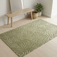 Green patterned rug on a wooden floor with a bench and plant in the background