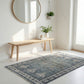 Nest living room with a blue patterned rug, wooden bench, and decorative items.