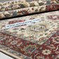 Close-up of a patterned rug with a visible brand label, featuring intricate designs and colors.