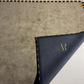 Navy fabric with gold trim and logo on a textured gray surface
