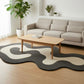 Modern living room with a gray sofa, wooden coffee table, and patterned rug.