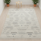 Patterned rug on a wooden floor with two potted plants in the background