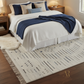 Bedroom with a neatly made bed featuring blue and white bedding, and a patterned rug.