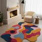 Colorful abstract rug in a modern living room with a fireplace and armchair.