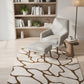 Modern living room with a gray armchair, ottoman, and patterned rug.
