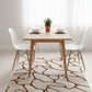 Dining area with a wooden table, white chairs, and a patterned rug.