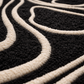 Black rug with white line art of a face in a living room setting