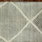 Close-up of a textured rug with geometric patterns on a wooden floor.