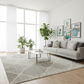 Modern living room with a gray sofa, coffee table, and decorative plants.