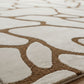 Close-up of a brown and beige patterned rug on a wooden floor.