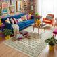 Colorful living room with a blue sofa, orange chair, and patterned rug.