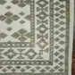 Geometric patterned rug with green and beige colors on a wooden floor.