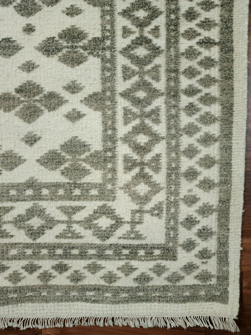 Geometric patterned rug with green and beige colors on a wooden floor.
