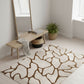 Modern interior with a patterned rug, wooden bench, and mirror.