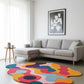 Modern living room with a colorful abstract rug, gray sectional sofa, and framed artwork.