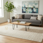 Modern living room with gray sofa, wooden coffee table, and abstract painting.