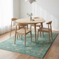 Dining table set with chairs on a blue patterned rug in a room with white walls.