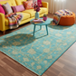 Living room with a blue floral rug, yellow sofa, and colorful decor.