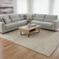 Modern living room with a gray sectional sofa, wooden coffee table, and decorative items.