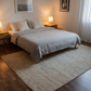 Neatly made bed in a bedroom with lamps and artwork on the walls.