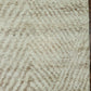 Textured beige rug with a subtle pattern on a wooden floor.
