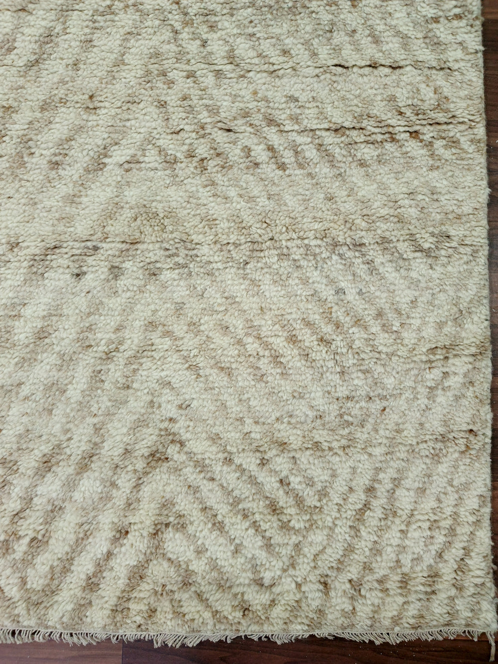 Textured beige rug with a subtle pattern on a wooden floor.